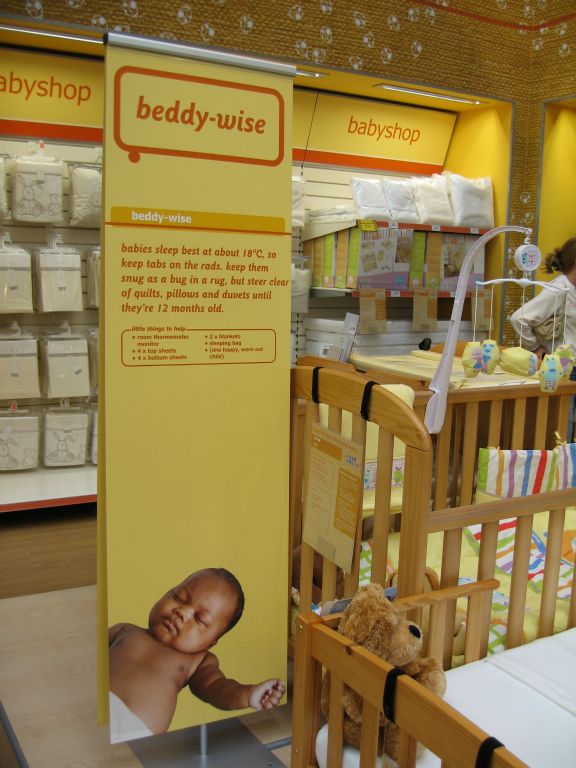Tall customer information signage about buying a baby's cot at the out-of-town Woolies store