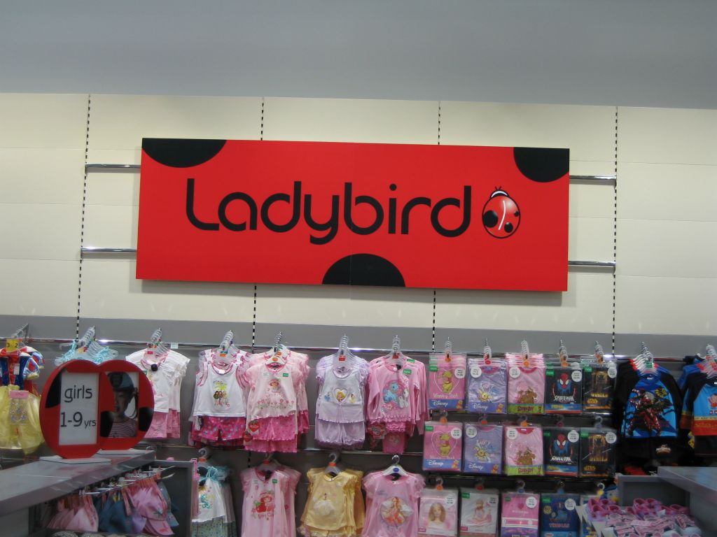 A bold wall-mounted directional sign for Ladybird Clothing at Woolworths (2005)