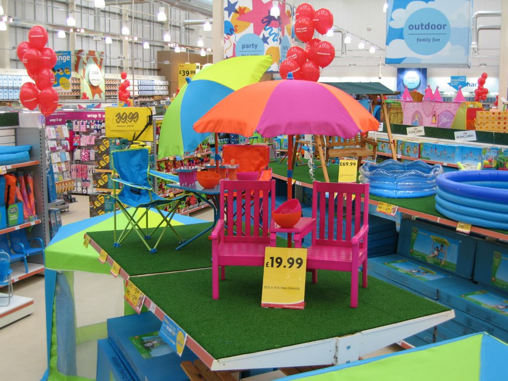 A pair of tete a tete pink chairs on a feature display with paddling pools in the background, from the seasonal range of an out-of-town Woolworths (2005)