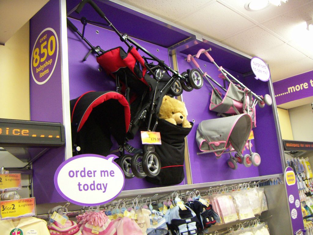 A display cabinet above the babywear displays at Woolworths Kingswood showcases examples from the retailer's range of Ladybird-branded pushchairs (2005)
