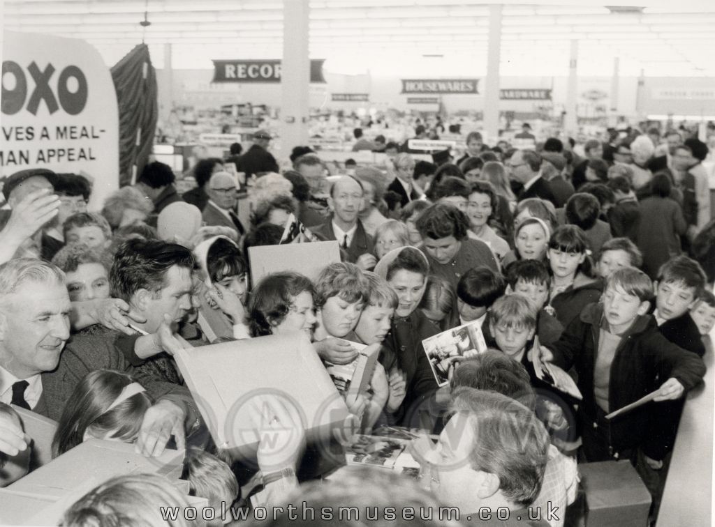 A huge throng of shoppers queue for autographs and copies of Katie's Cookbook from Katie and Phillip, stars of OXO's popular Sixties advertising campaign.  You can see the Record, Housewares and Hardware Departments in the Background.